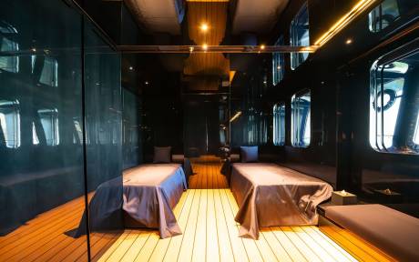 A dimly lit, cozy interior of a train car with wooden floors and benches covered in purple linens, creating an intimate and inviting atmosphere.
