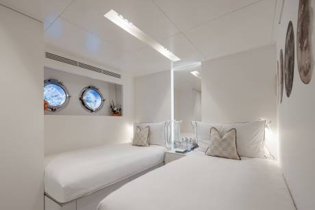 A cozy and bright bedroom with white walls, circular windows, and decorative pillows on the bed.