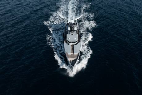 A large, sleek yacht cutting through the deep blue waters, leaving a trail of white foam in its wake.