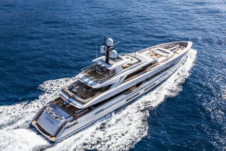 A luxurious white yacht cruises through the deep blue ocean, leaving a white wake behind it.
