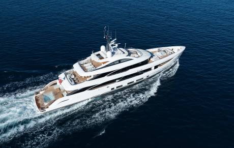 A luxurious white yacht with a pool on its stern cruises through the deep blue ocean, leaving a white wake behind it.