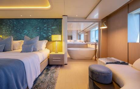 A luxurious bedroom with a king-sized bed in the foreground and a modern bathroom with a freestanding tub in the background.