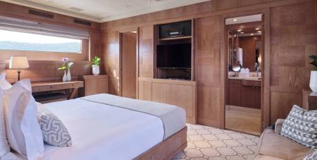 A luxurious bedroom with a large bed in the foreground and a glimpse into a well-lit bathroom in the background.