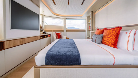 A luxurious bedroom with a large bed in the foreground and a scenic view through the windows in the background.