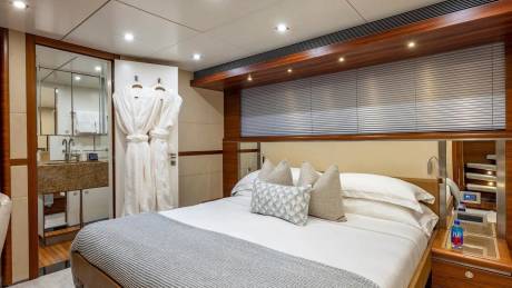 A luxurious bedroom with a plush bed in the foreground and a modern bathroom with plush robes in the background.
