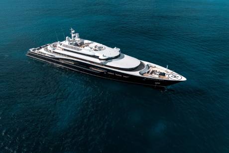 A luxurious superyacht with a helipad on its bow floats serenely on the deep blue ocean.