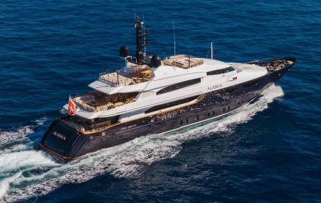 A luxury yacht named "Alaska" cruises through deep blue ocean waters, leaving a white wake in its path.