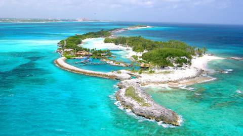 Azure waters surround a lush island paradise dotted with palm trees, white sand beaches, and tranquil lagoons.