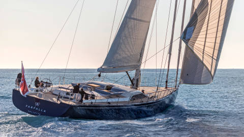 The sleek yacht Farfalla cuts through the sparkling blue water under a clear sky.