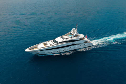 A sleek white yacht glides through the deep blue ocean, leaving a foamy wake behind it.