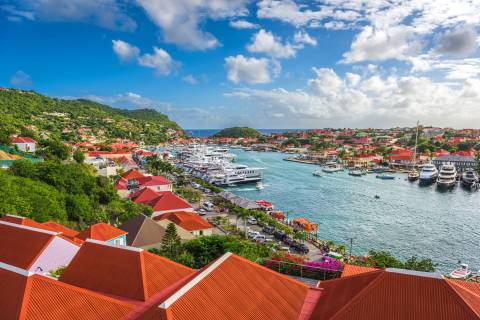 Luxury yachts fill the harbor of this vibrant coastal town nestled against lush green hills.