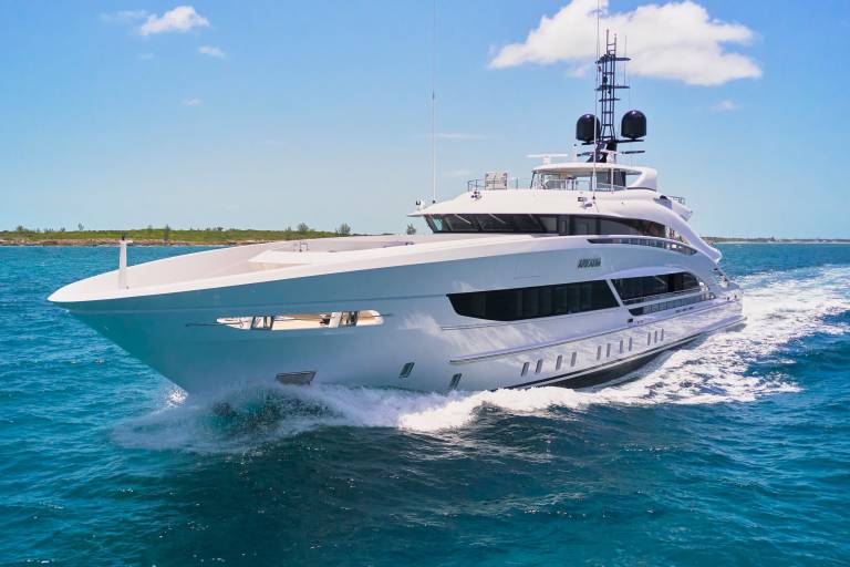The sleek white yacht Arkadia cuts through the turquoise waters under a bright blue sky.