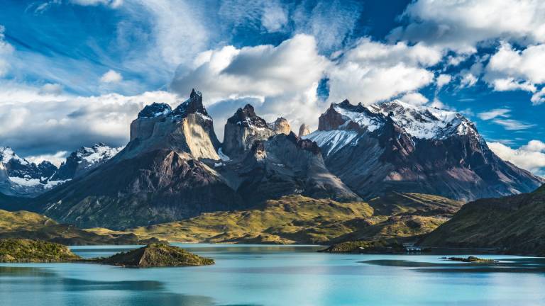 Majestic snow-capped peaks rise dramatically above a serene turquoise lake in this breathtaking Patagonian landscape.