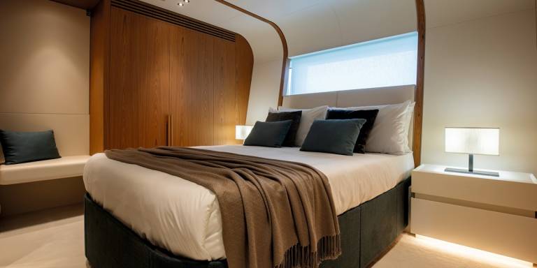 A luxurious bedroom features a plush bed adorned with a warm throw and elegant pillows, complemented by rich wood paneling and a modern bedside lamp.