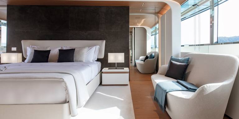 Luxurious modern yacht interiors feature a spacious bedroom and a cozy seating area with stunning ocean views.