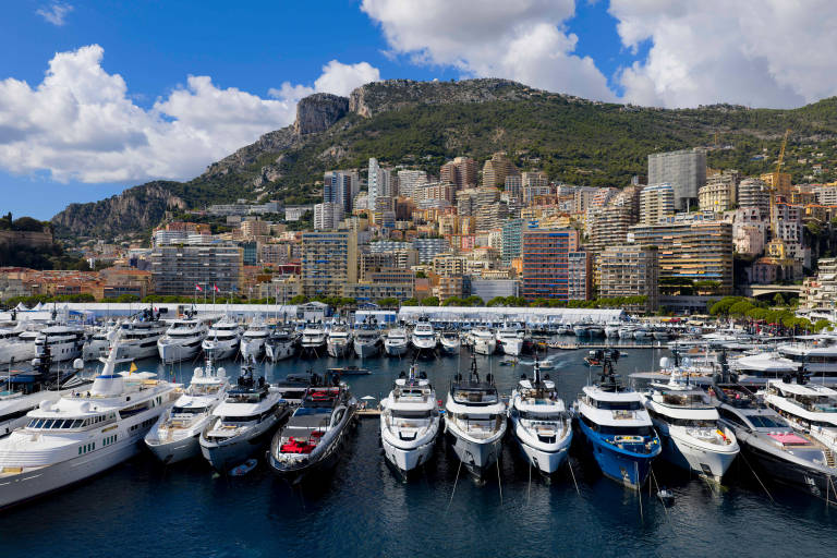 Luxurious yachts fill the harbor of Monaco with the stunning cityscape and mountains as a backdrop.