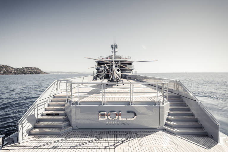 The superyacht BOLD, with its helipad and luxurious amenities, cruises through the tranquil Mediterranean Sea.