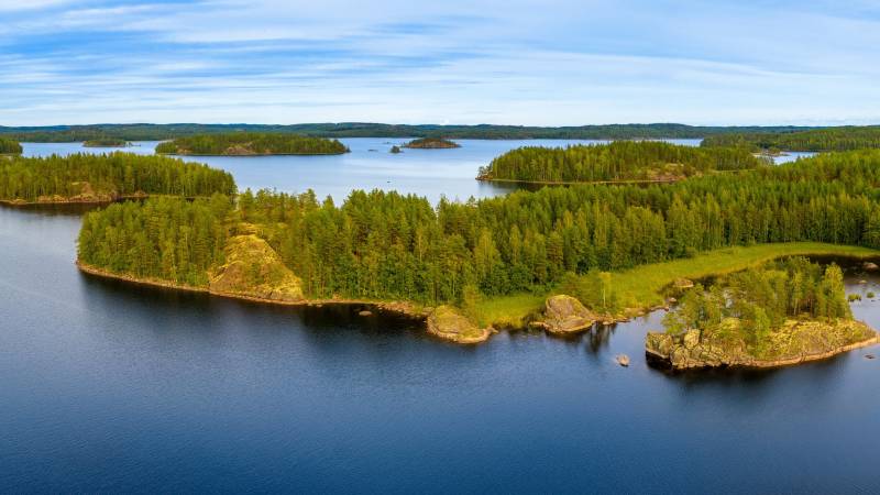 Lush green islands dot the serene blue waters of this tranquil lake under a vast sky.
