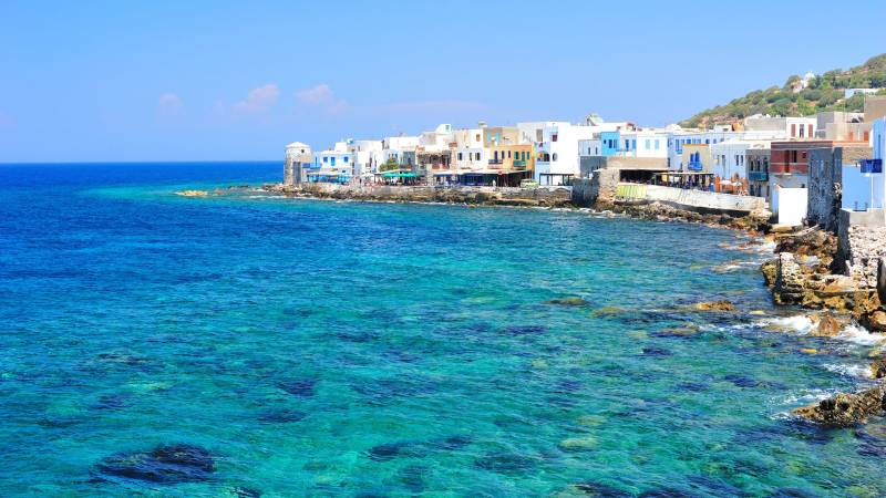 Charming white-washed buildings line the turquoise waters of a picturesque coastal village.