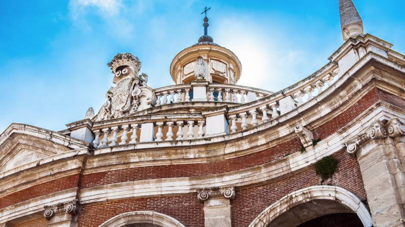 The ornate facade of a historic building, adorned with intricate carvings and a grand dome, reaches towards a bright blue sky.